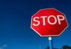 Red stop sign against a clear blue sky.