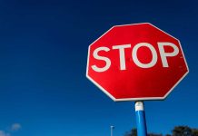 Red stop sign against a clear blue sky.