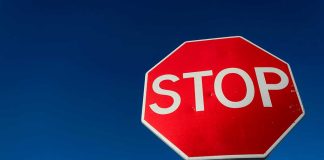 Red stop sign against a clear blue sky.