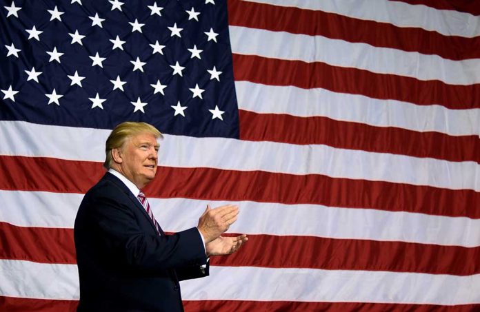 Man clapping in front of large American flag