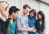 Group of five friends looking at a smartphone.