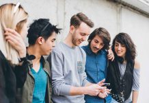 Group of five friends looking at a smartphone.