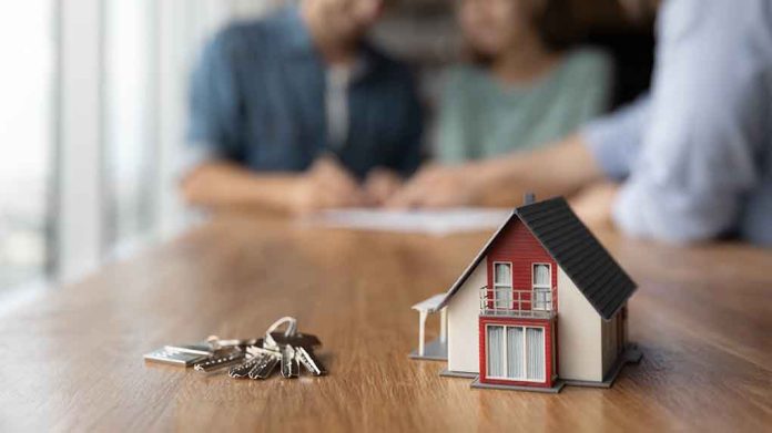 Model house and keys with couple signing documents.