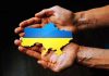 Hands holding Ukraine map with flag design.