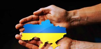 Hands holding Ukraine map with flag design.