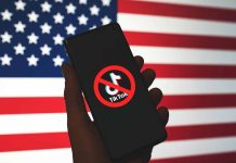 Hand holding phone with banned TikTok symbol USA flag