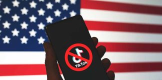 Hand holding phone with banned TikTok symbol USA flag