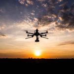 Drone flying against sunset sky.