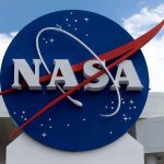 NASA logo on building exterior with cloudy sky.