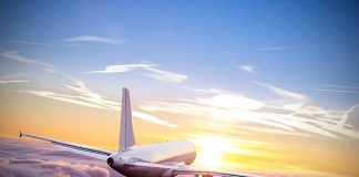 Airplane flying above clouds during sunset sky