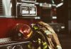 Firefighter helmet and gear beside a fire truck.