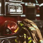 Firefighter helmet and gear beside a fire truck.