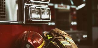 Firefighter helmet and gear beside a fire truck.