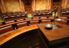 Empty courtroom with scales of justice in foreground.