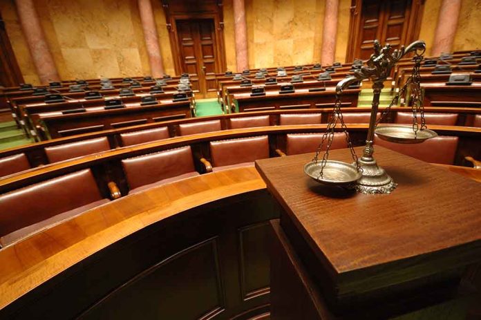 Empty courtroom with scales of justice in foreground.