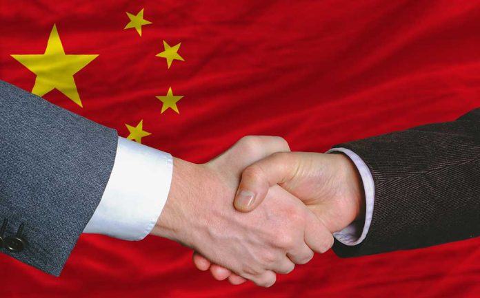 Two people shaking hands, Chinese flag background.