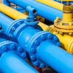 Blue and yellow industrial gas pipes with valves.