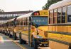 School buses lined up in front of building.