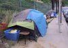 Tents and belongings set up along sidewalk.