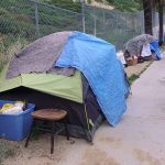 Tents and belongings set up along sidewalk.