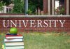 Books and apple in front of university sign