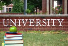 Books and apple in front of university sign