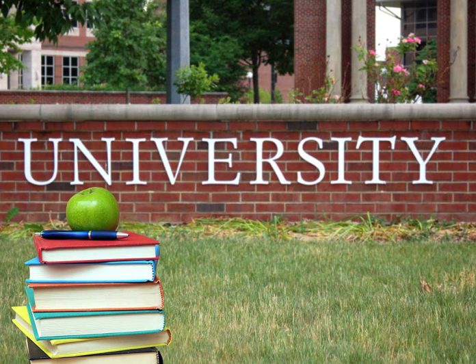 Books and apple in front of university sign