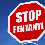 Stop sign saying "Stop Fentanyl" against sky.