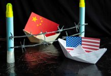 China and USA flags in paper boats with barbed wire.