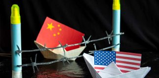 China and USA flags in paper boats with barbed wire.