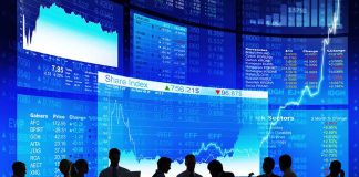 Silhouetted people in front of stock market displays.