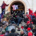 Crowd at building entrance, people wearing red hats.