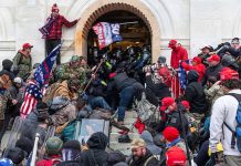 Crowd at building entrance, people wearing red hats.