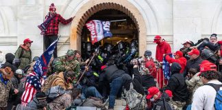 Crowd at building entrance, people wearing red hats.