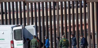 Border patrol agents detaining individuals near a fence