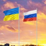 Ukrainian and Russian flags against vibrant sunset sky