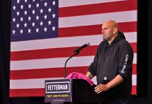 Person speaking at podium with American flag backdrop