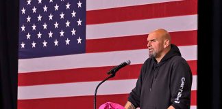 Person speaking at podium with American flag backdrop