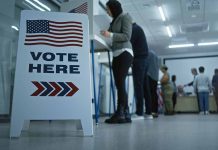 Sign reading "Vote Here" in a polling station.