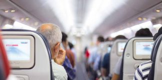 Passengers seated in airplane cabin with screens visible