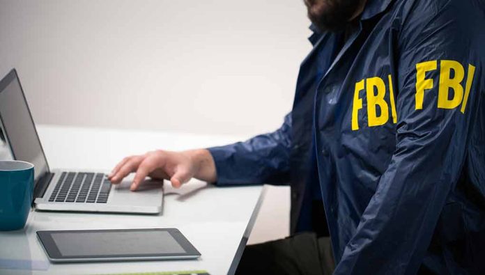 Person in FBI jacket using laptop at desk