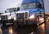 Two trucks driving on a wet road.