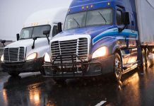 Two trucks driving on a wet road.