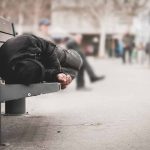 Person sleeping on a bench in a public area.