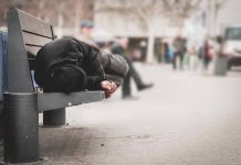 Person sleeping on a bench in a public area.