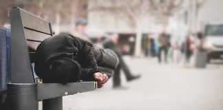 Person sleeping on a bench in a public area.