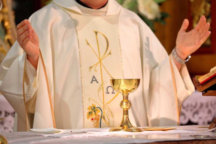 Priest in white robe with chalice and book