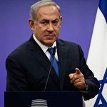 Prime minister Benjamin Netanyahu pointing to the camera in front of Israeli flag