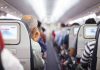 Passengers seated in airplane cabin with screens visible