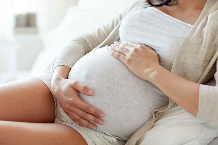 Pregnant woman holding her belly, sitting comfortably.